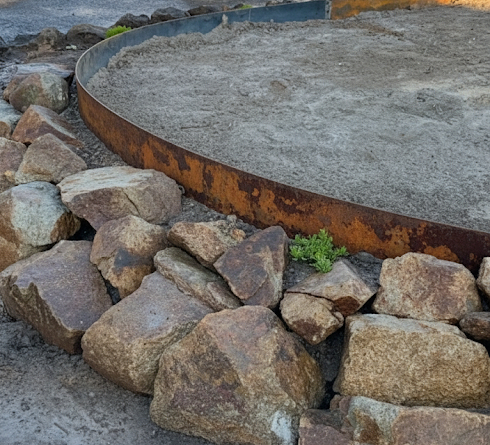 Sharp steel garden edging separating a lawn from a garden bed.