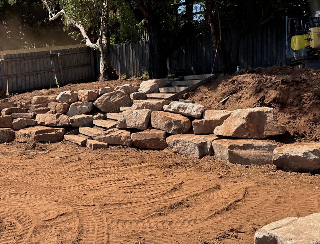 Excavator preparing the base for a retaining wall.